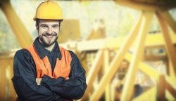 smiling worker in protective uniform and protective helmet